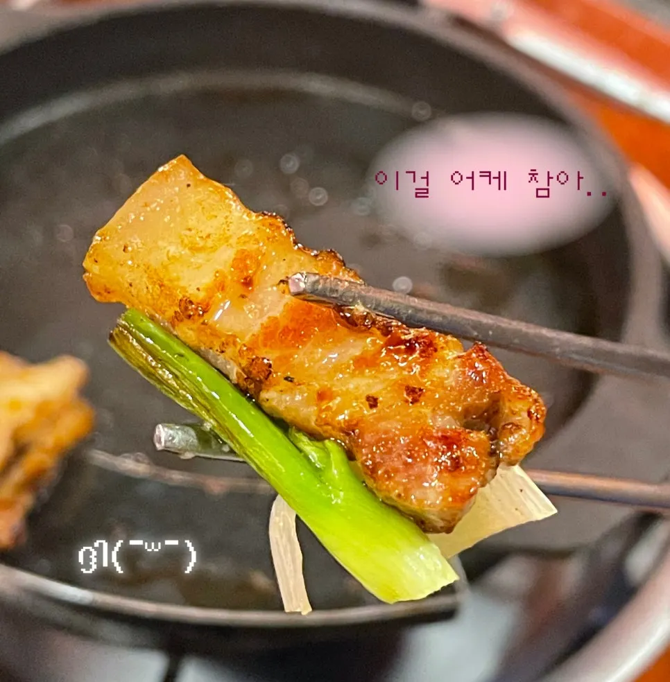 젓가락으로 집어 든 촉촉한 삼겹살 한 점