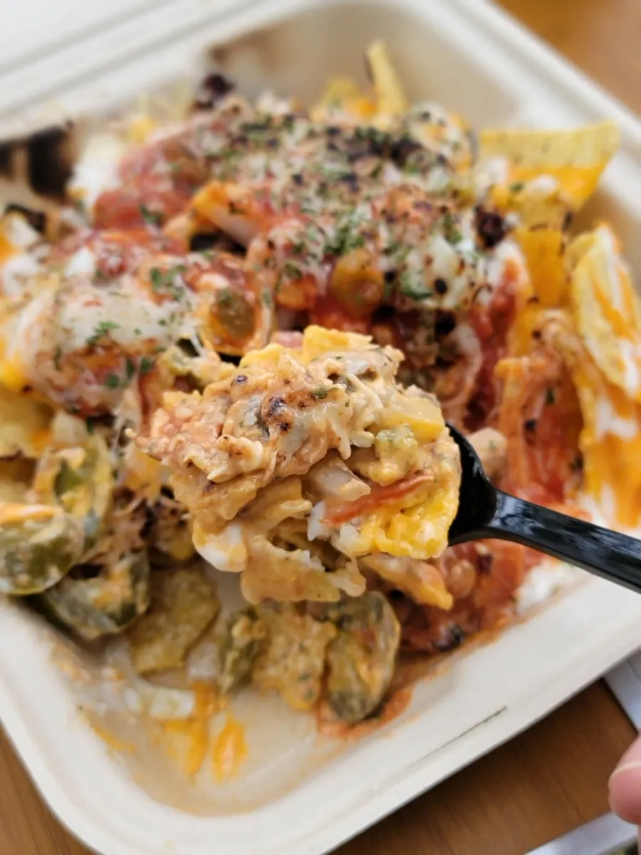 A spoonful of nachos mixed with sauce