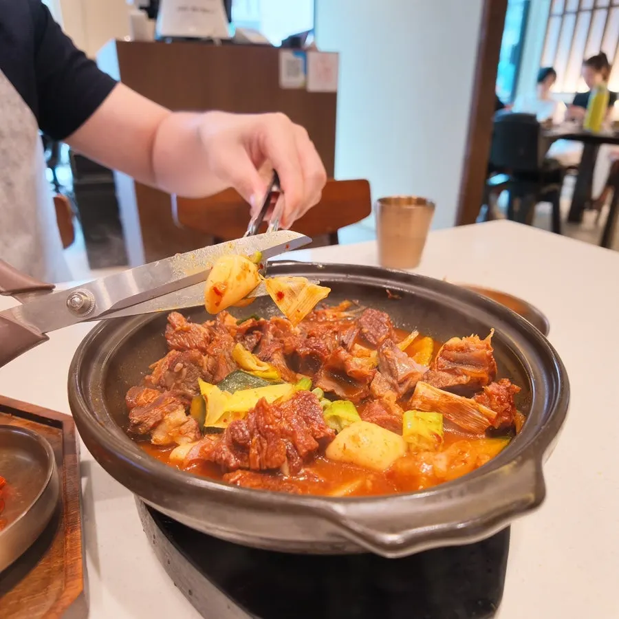 Spicy braised beef short ribs bubbling at the table
