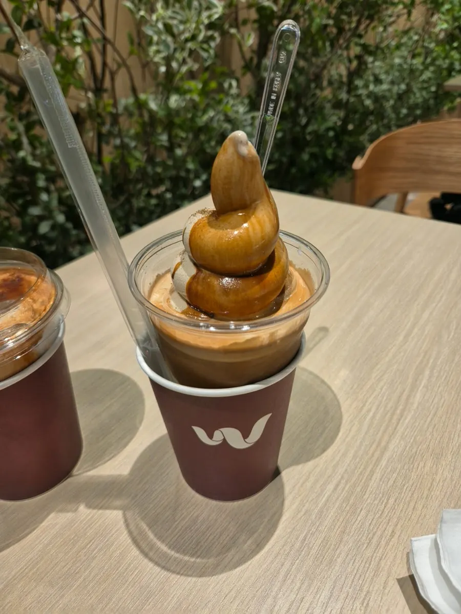 A cup of hojicha Wunder Gato with a clear spoon stuck in it