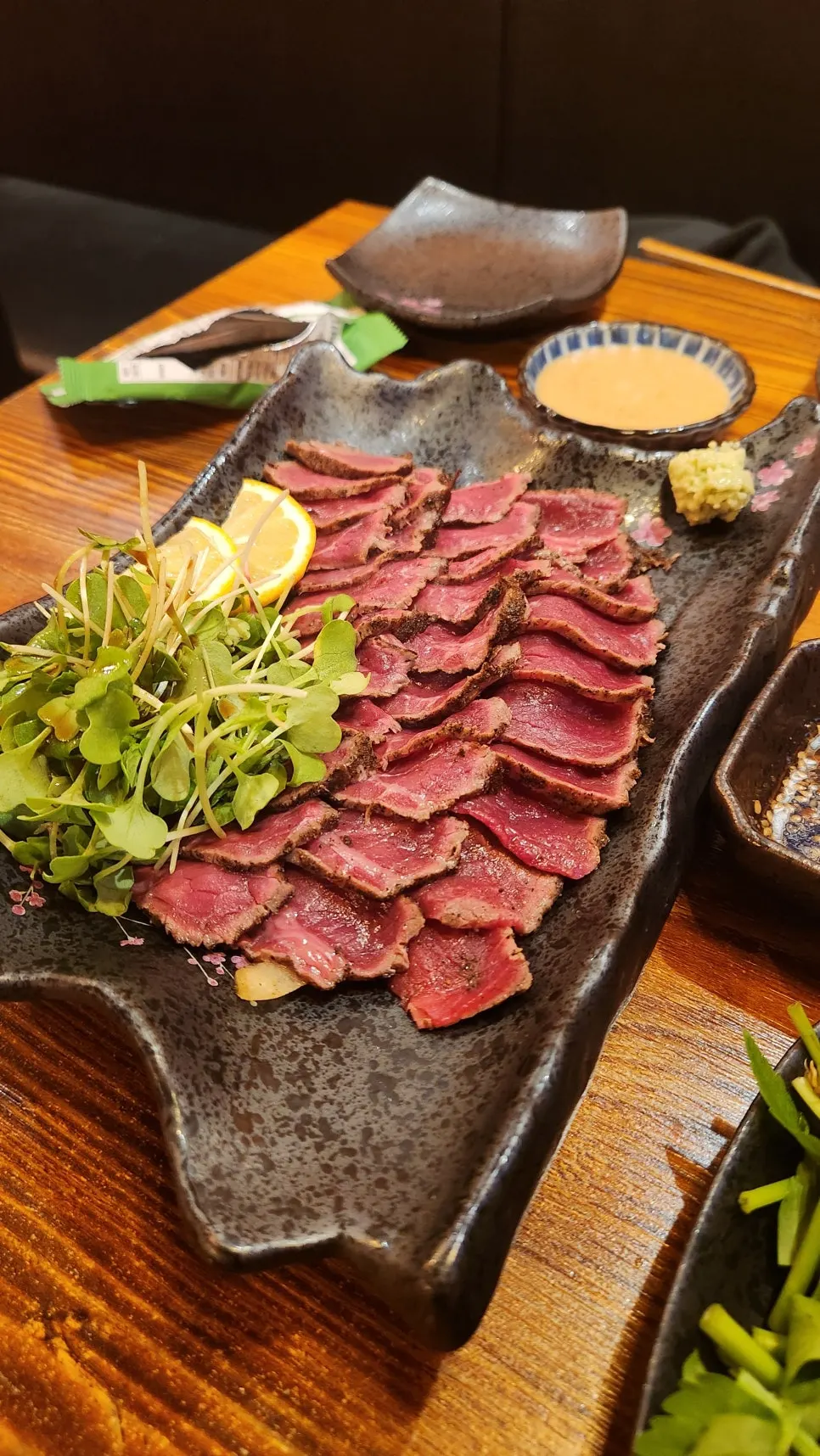 Beef sashimi served with seaweed, radish sprouts, cheese, and sauce