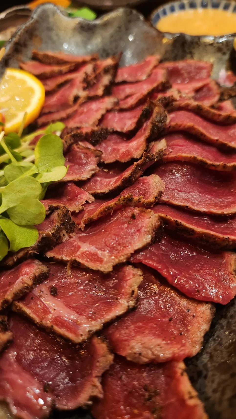 A piece of beef sashimi placed on minari