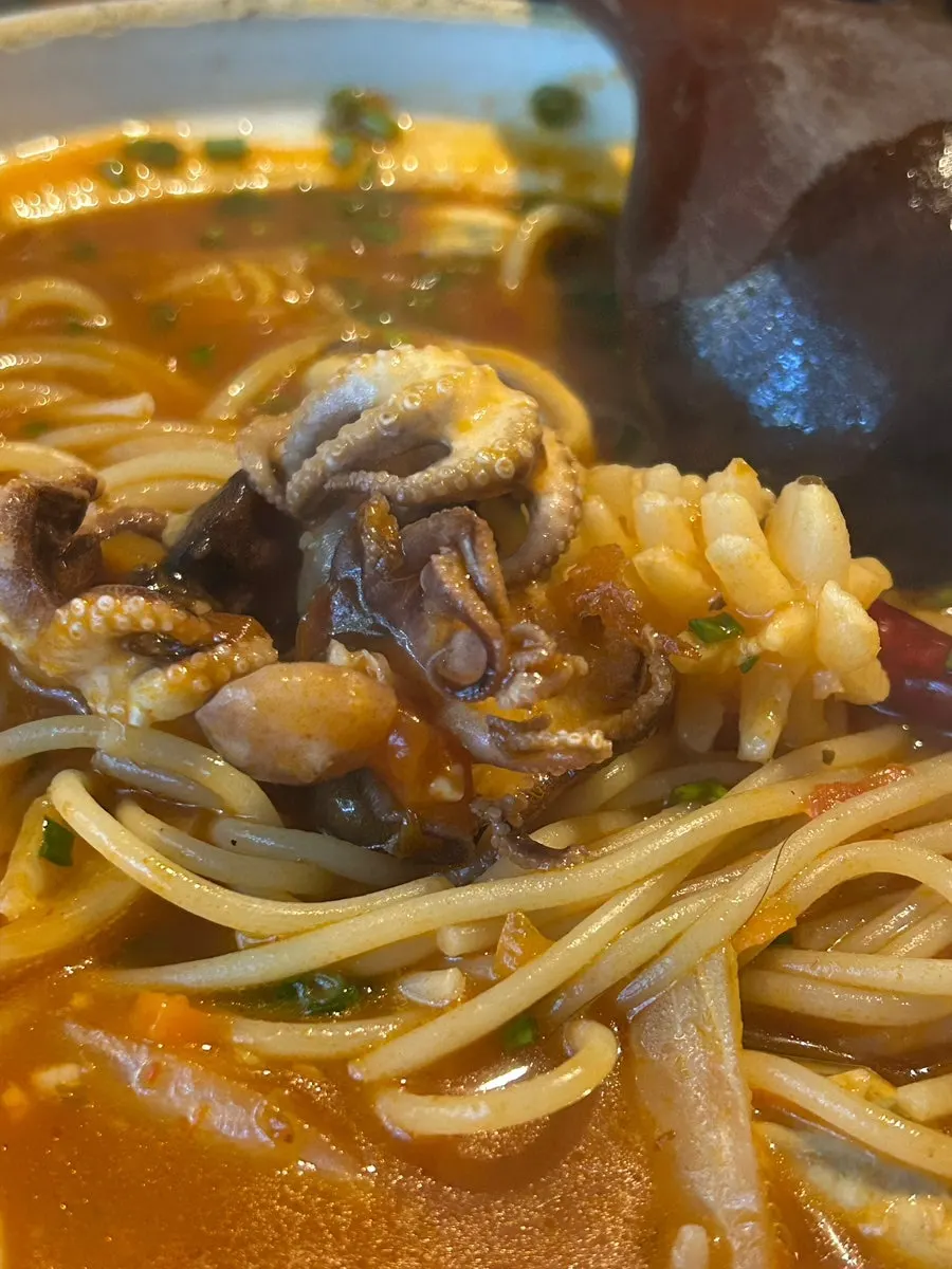 Baby octopus, mussels, shrimp, and squid inside the tomato nabe