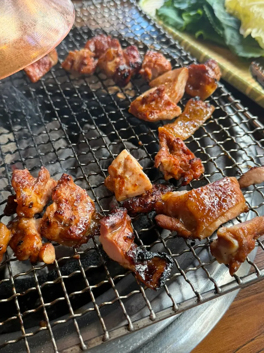 Flipping the charcoal dakgalbi with tongs