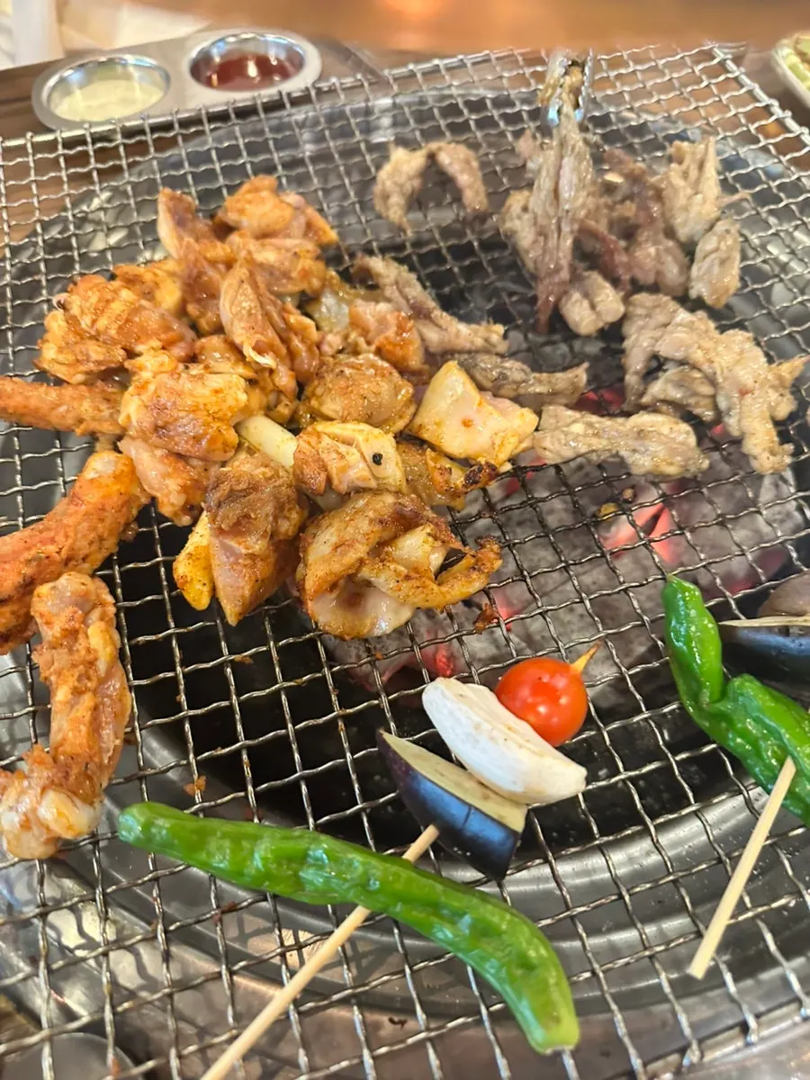 숯불 위에서 익어가는 양념 닭갈비와 닭목살