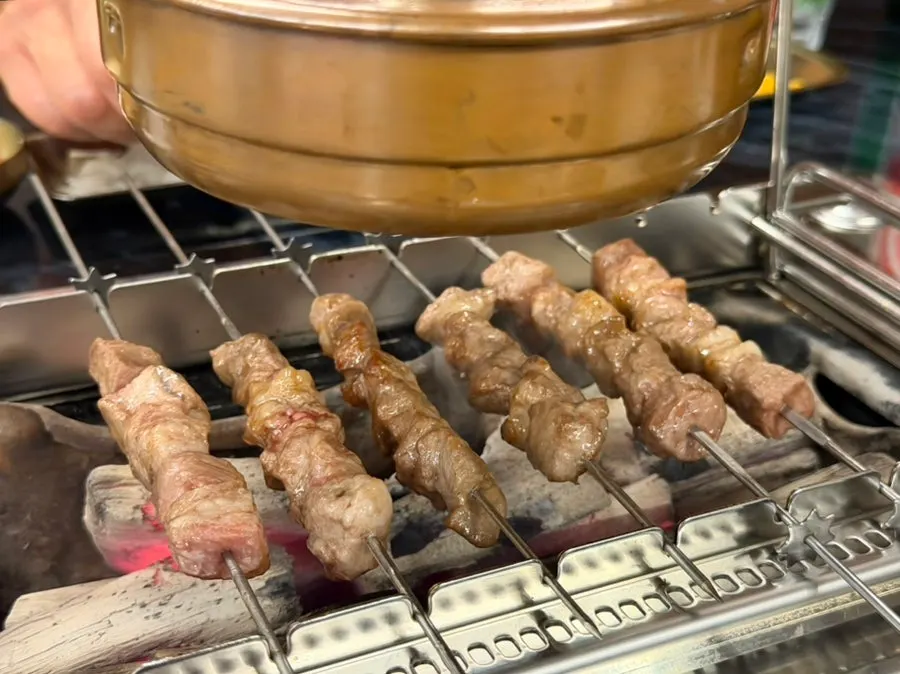 Skewers turning golden brown on the rotating charcoal grill