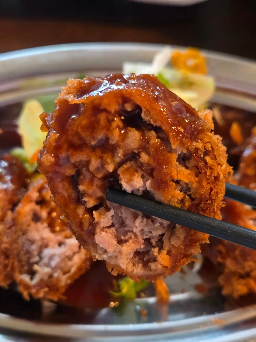 Dipping the menchi katsu in the special sauce
