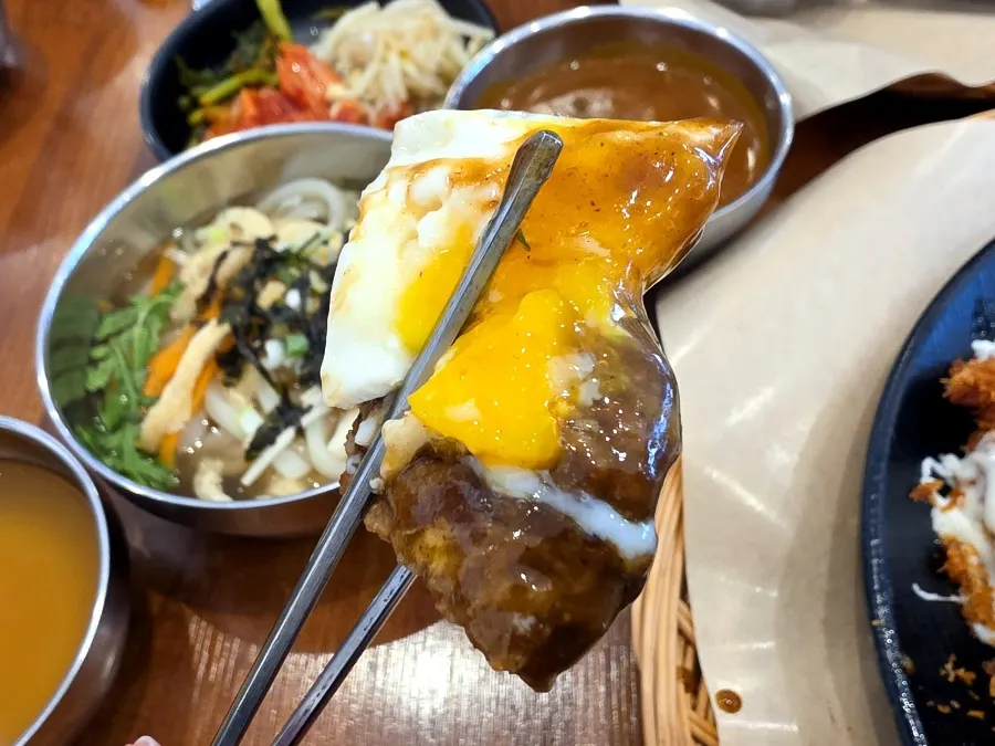Demi hamburg with a burst egg yolk, rice, and salad