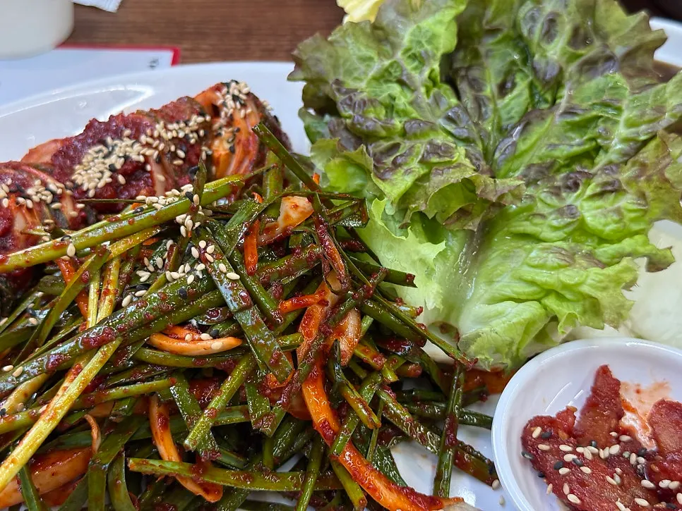 Kimchi and seasoned chives served alongside the bossam platter