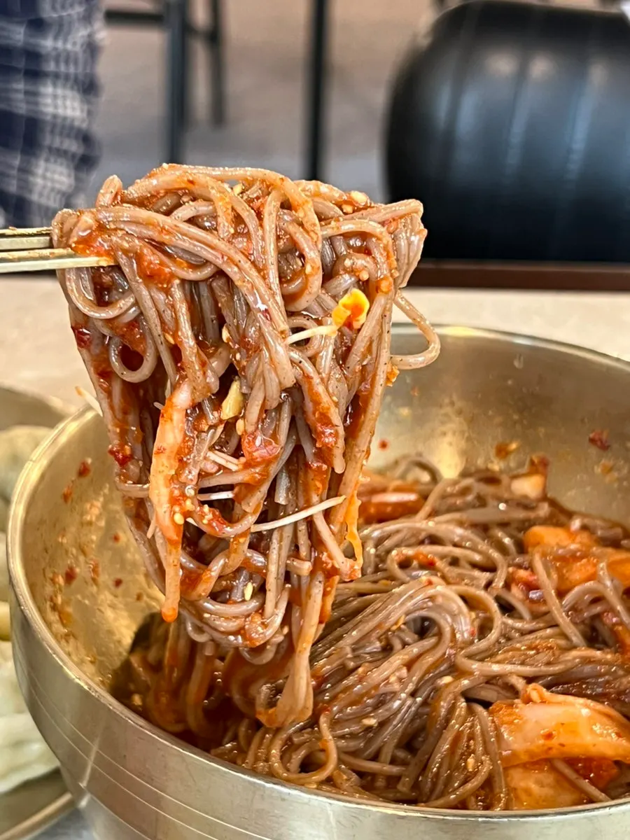 보쌈 한 점을 막국수 면에 말아 올린 모습