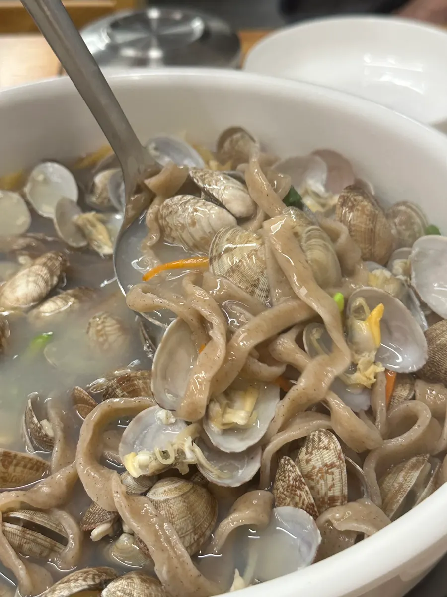 A photo of scooping up the buckwheat clam noodle soup with a ladle