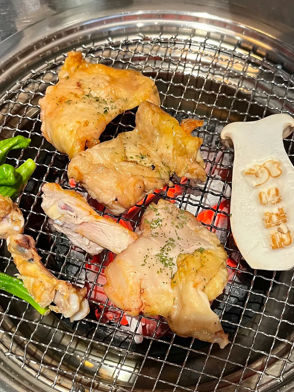 Chicken galbi prepared and placed on the grill by staff