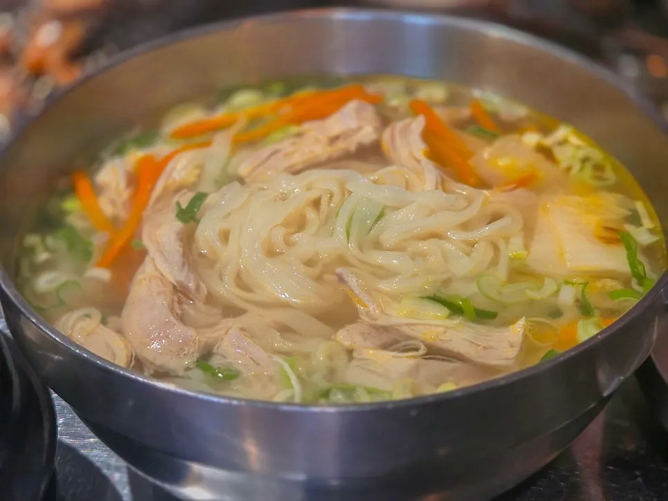Chicken kalguksu topped with shredded chicken and vegetables