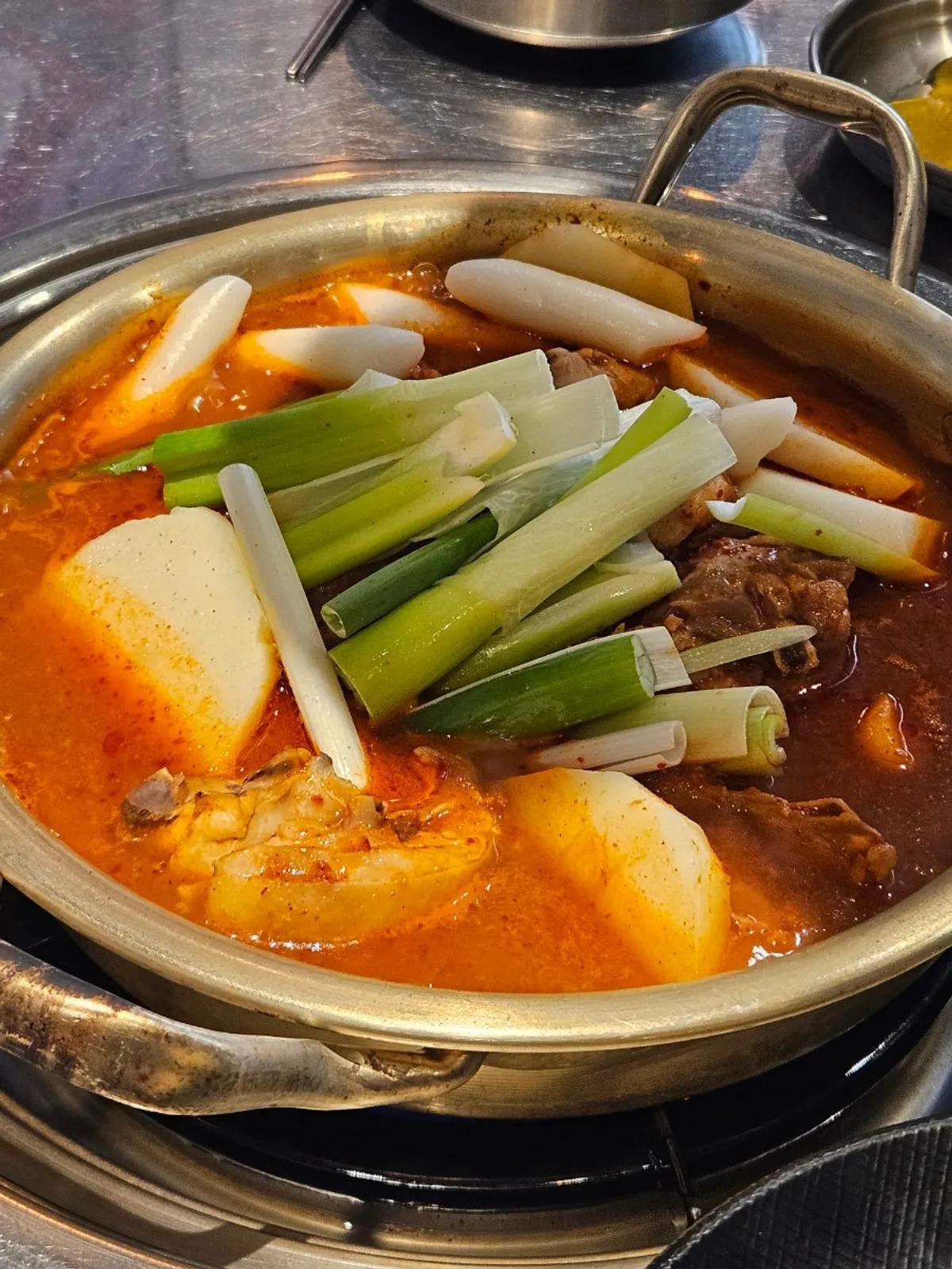 Yanggyegok's dakdoritang topped with green onion, potato, and rice cake
