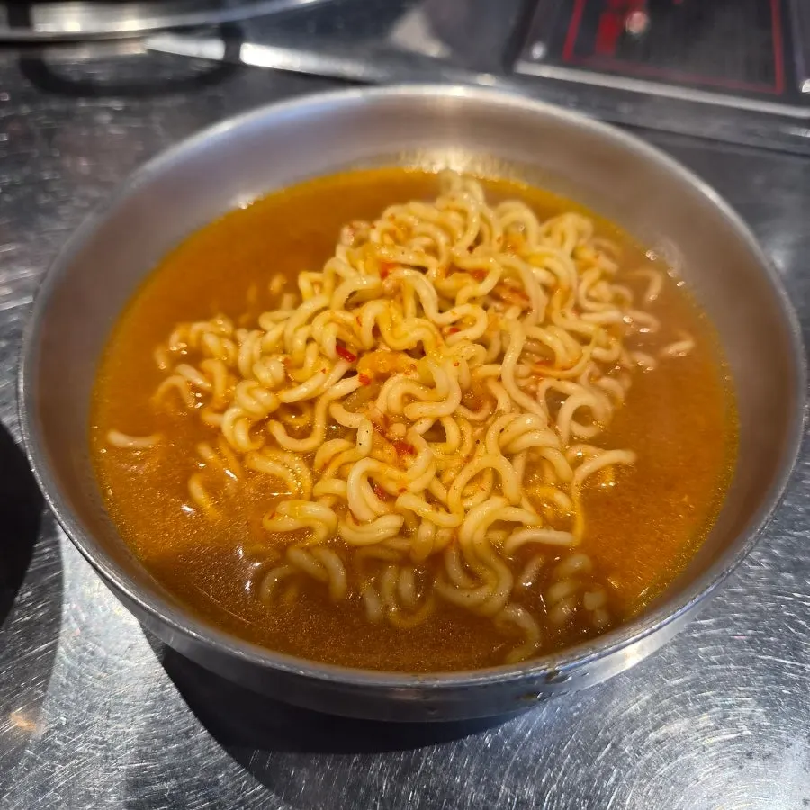 Firm ramen noodles lifted out, coated in the sauce