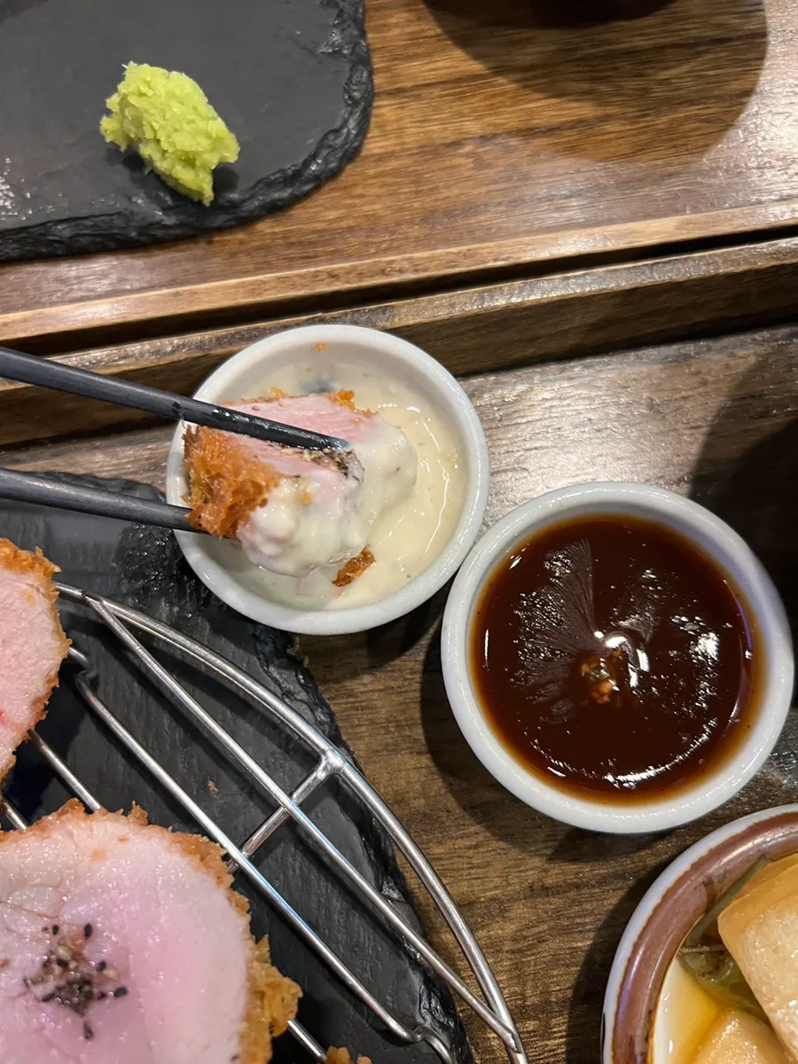 A piece of hire katsu dipped in tonkatsu sauce