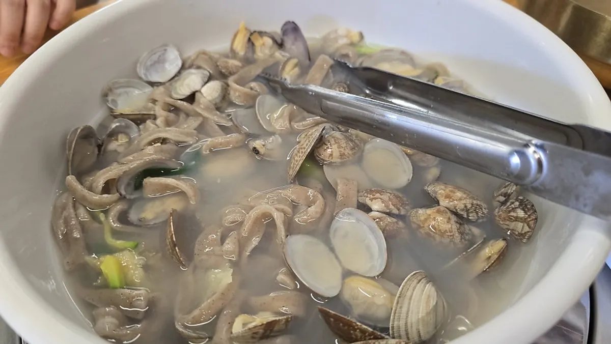 Buckwheat clam kalguksu piled high with clams