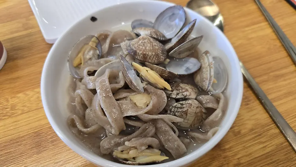Wide buckwheat noodles revealed after clearing away the clams