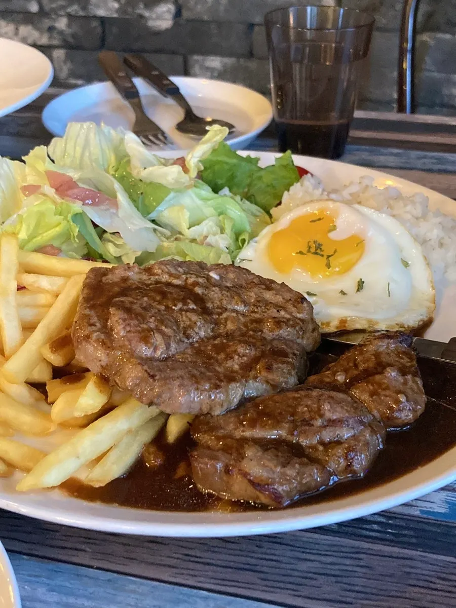 A plate of pork neck steak topped with a soft fried egg