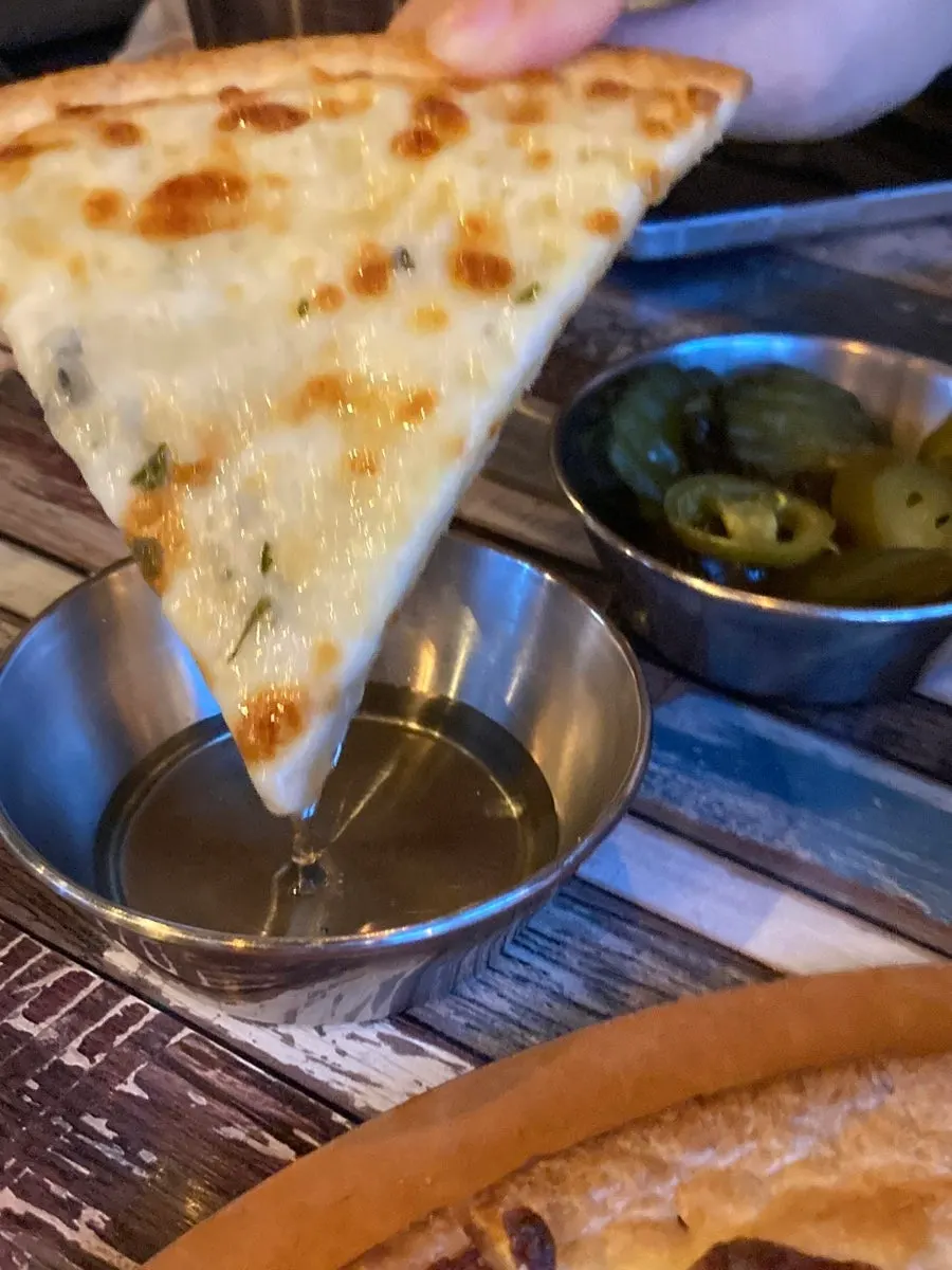 A slice of gorgonzola pizza with handmade pickles