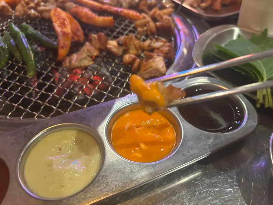 Dipping charcoal-grilled dakgalbi into sauce