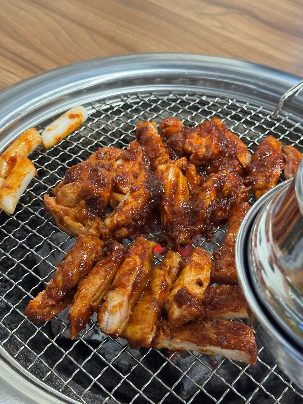 Pre-grilled marinated dakgalbi poured onto the pan over charcoal