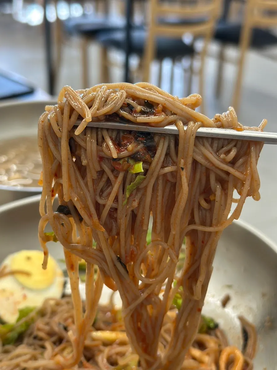 A chopstick-full of mixed bibim makguksu