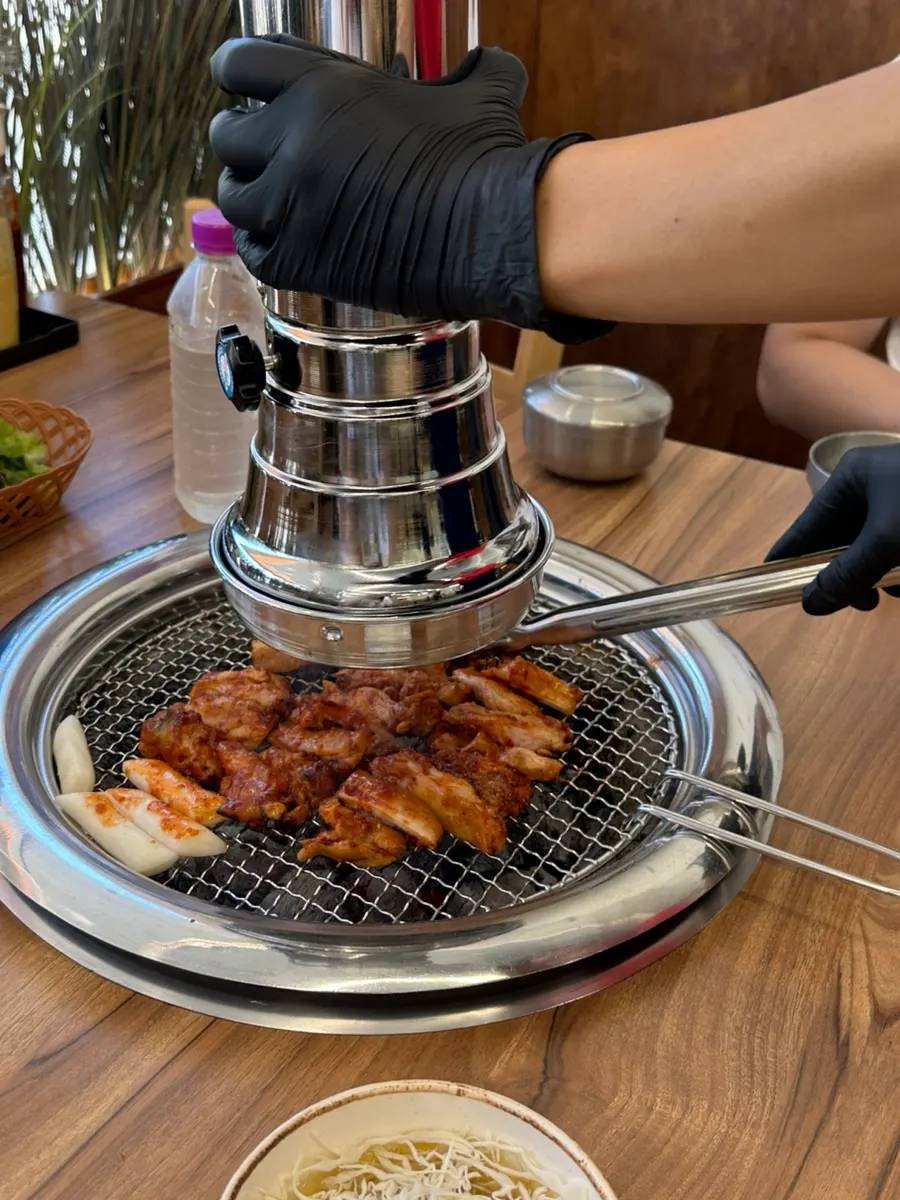 Staff member flipping the charcoal dakgalbi while grilling
