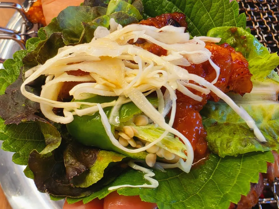 One portion each of sweet and soy dakgalbi grilling side by side