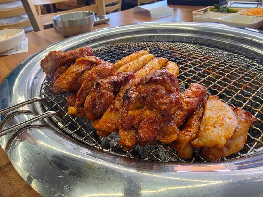 Dakgalbi and rice cakes grilling over charcoal