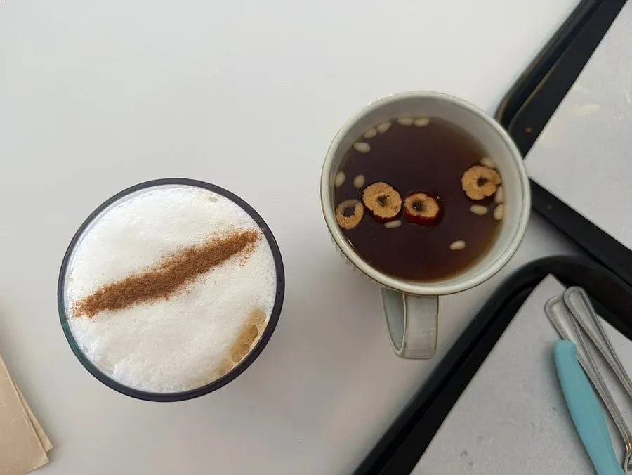 A table with cappuccino, pear-bellflower quince tea, and bread