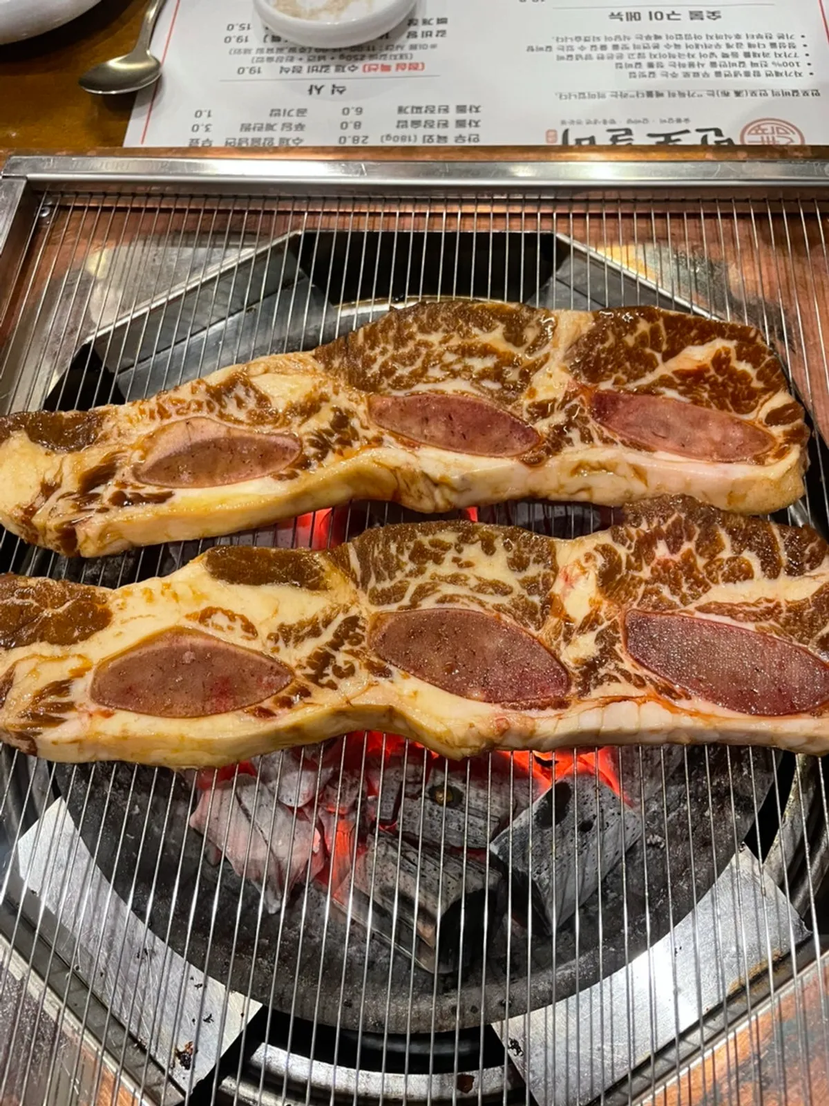 Raw beef short ribs grilling over charcoal
