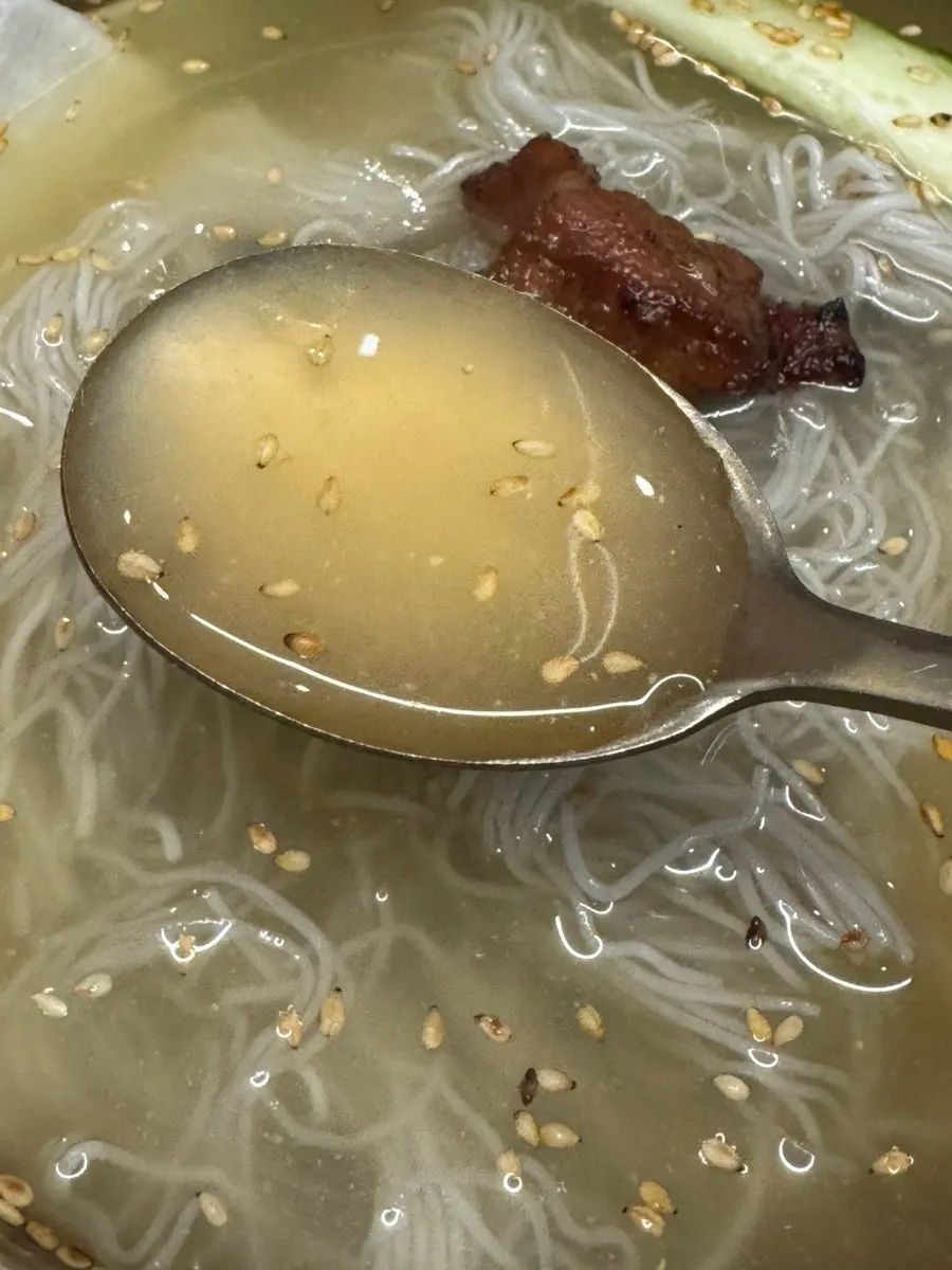 Naengmyeon noodles lifted with chopsticks