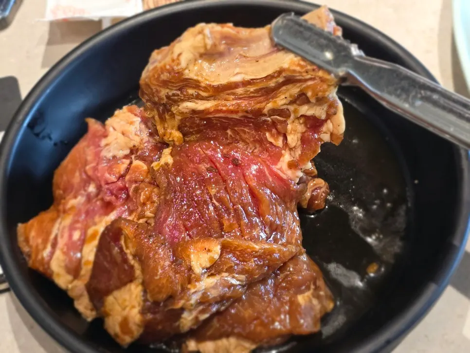 Handmade seasoned galbi spread out and grilling