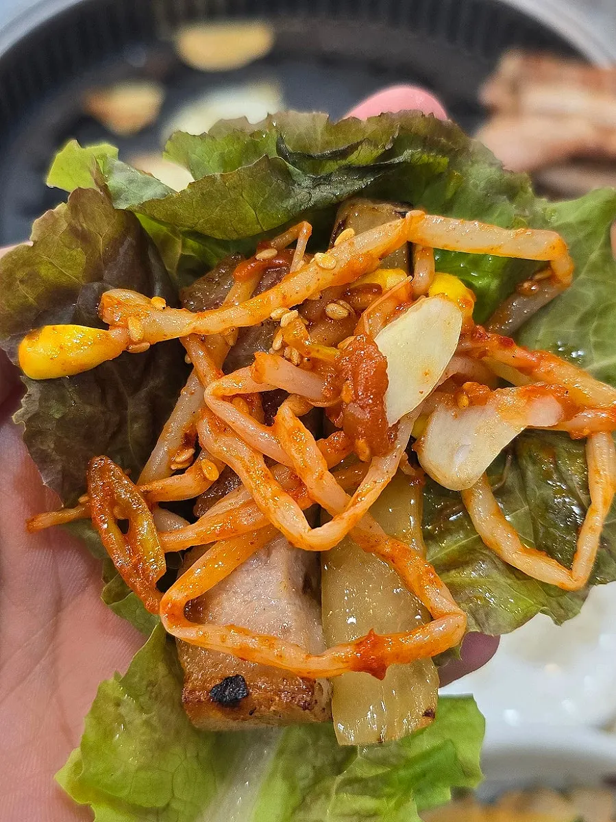 A lettuce wrap piled with meat and side dishes