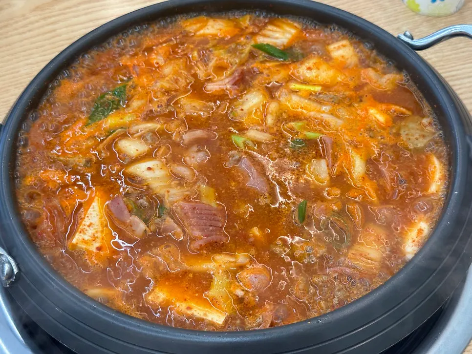 A full table spread of budae-jjigae with the egg roll set
