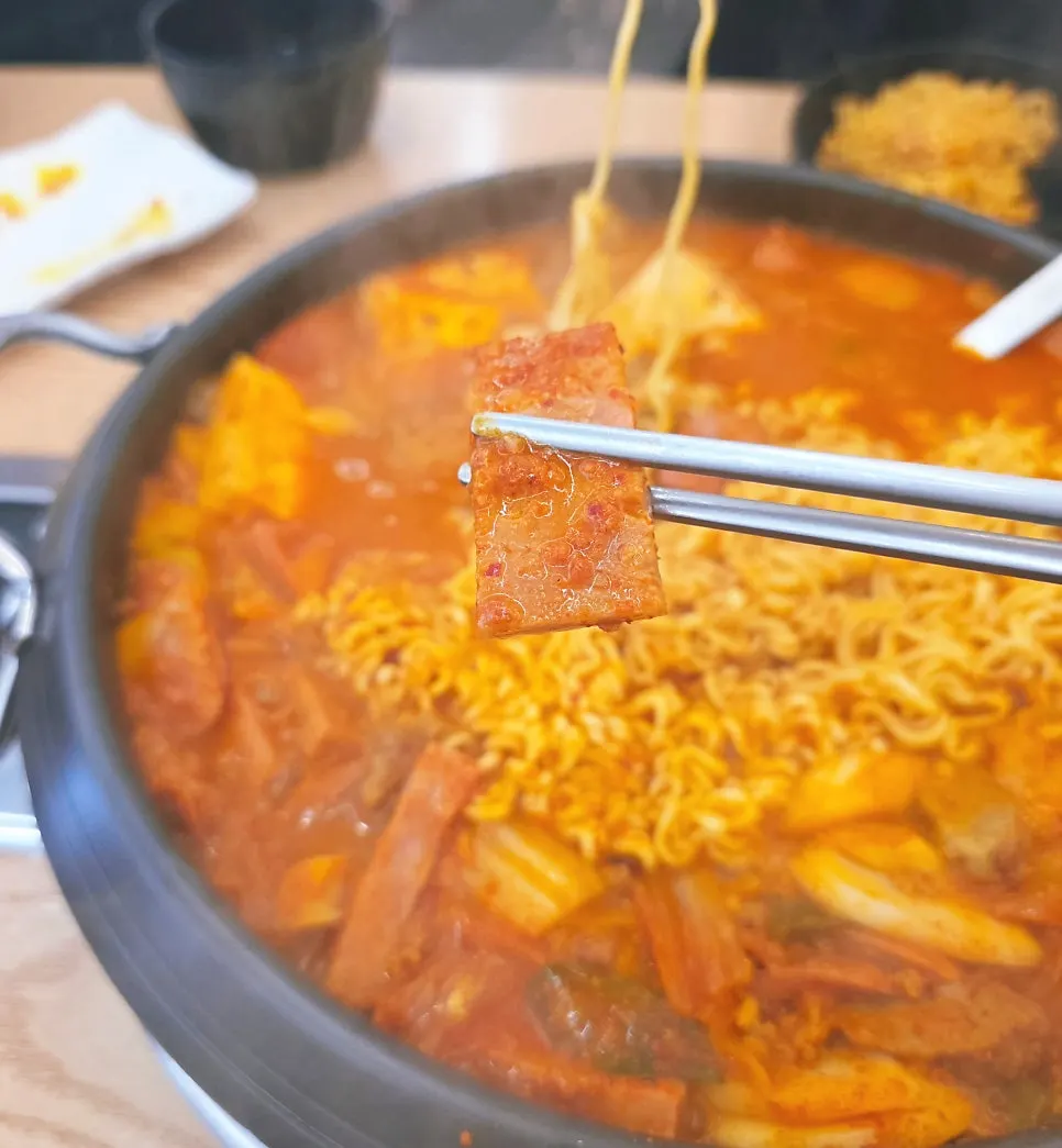 Budae-jjigae broth deepening in color as it simmers