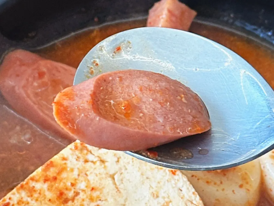 Ladle scooping up broth and ingredients from the budae-jjigae