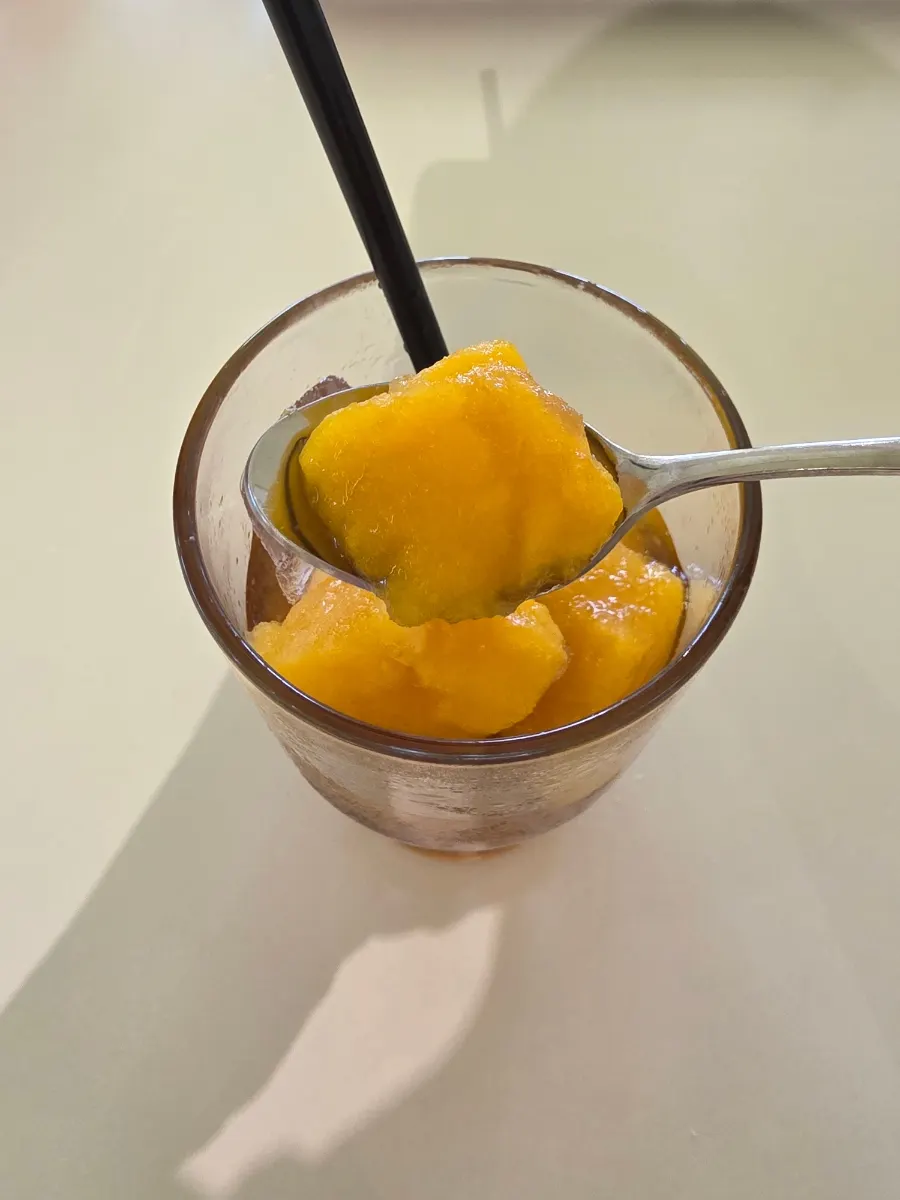 Spooning up frozen mango from inside the amangchu
