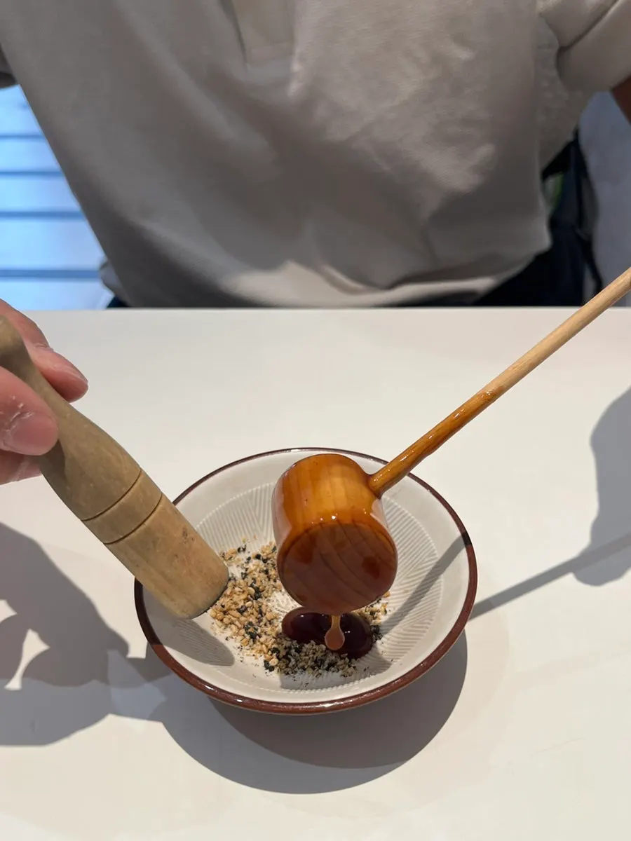 Pouring tonkatsu sauce over the ground sesame