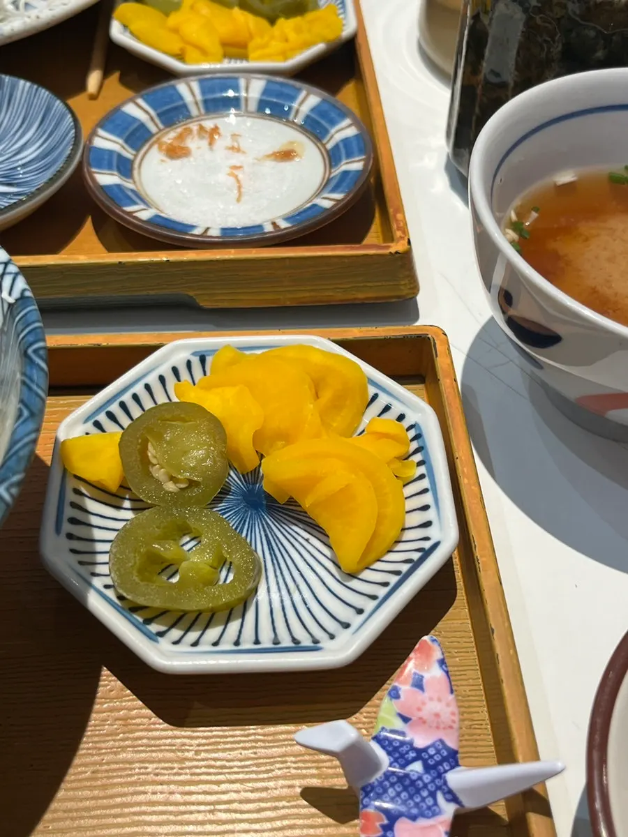 A piece of katsu next to a bowl of tonkatsu sauce