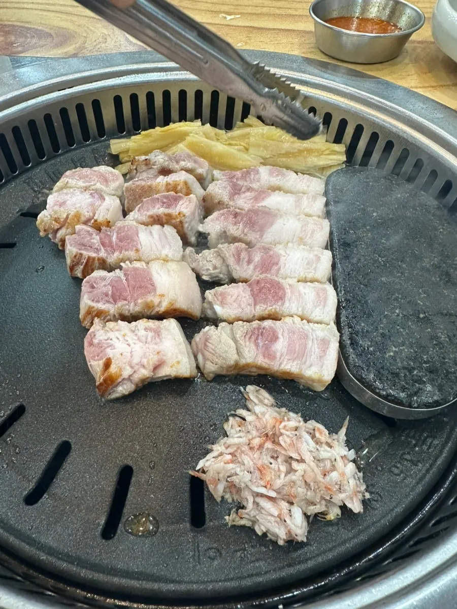 Staff cutting and grilling thick pork belly with scissors