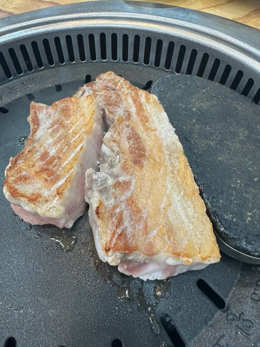 Aged pork belly and kimchi cooking on the grill