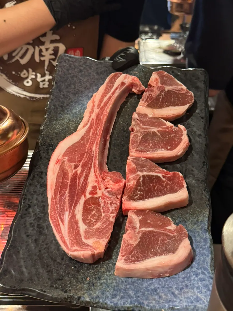 Lamb ribs and T-bone steak grilling over charcoal