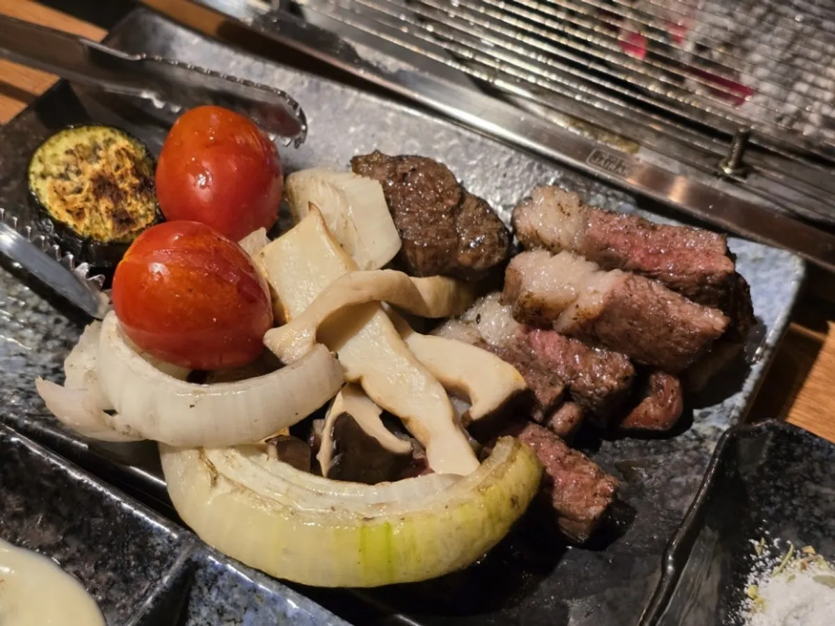 Grill with lamb, vegetables, and fruit cooking together