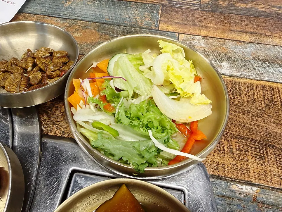 Plate of basic side dishes including salad and silkworm pupae