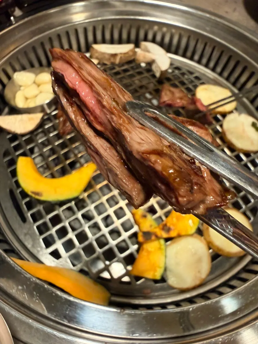 A piece of 1++ Korean beef lifted with tongs