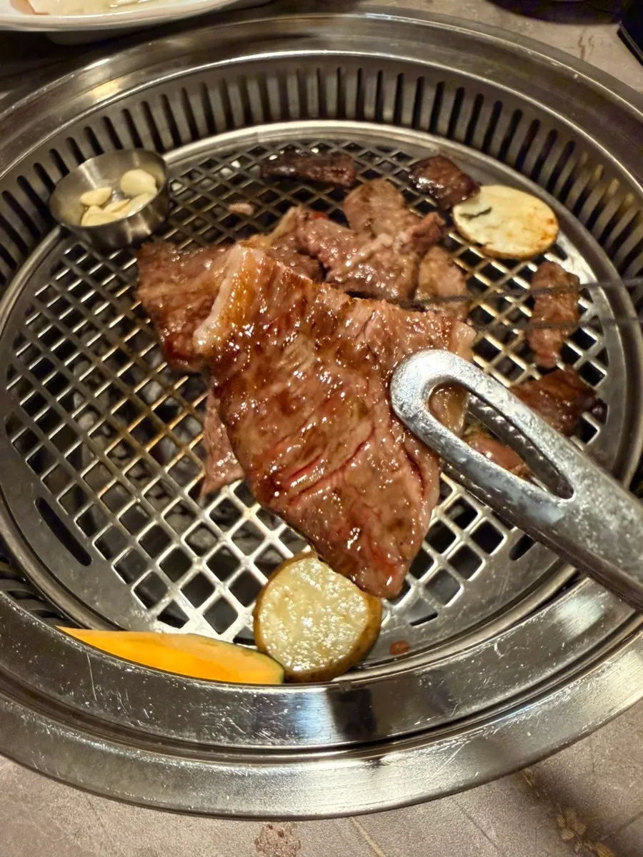 A piece of grilled deungsim lifted from the grill