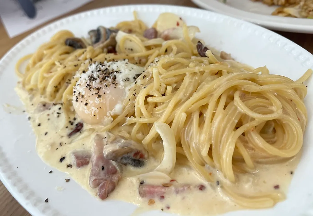 Table setting with carbonara and seafood tomato pasta