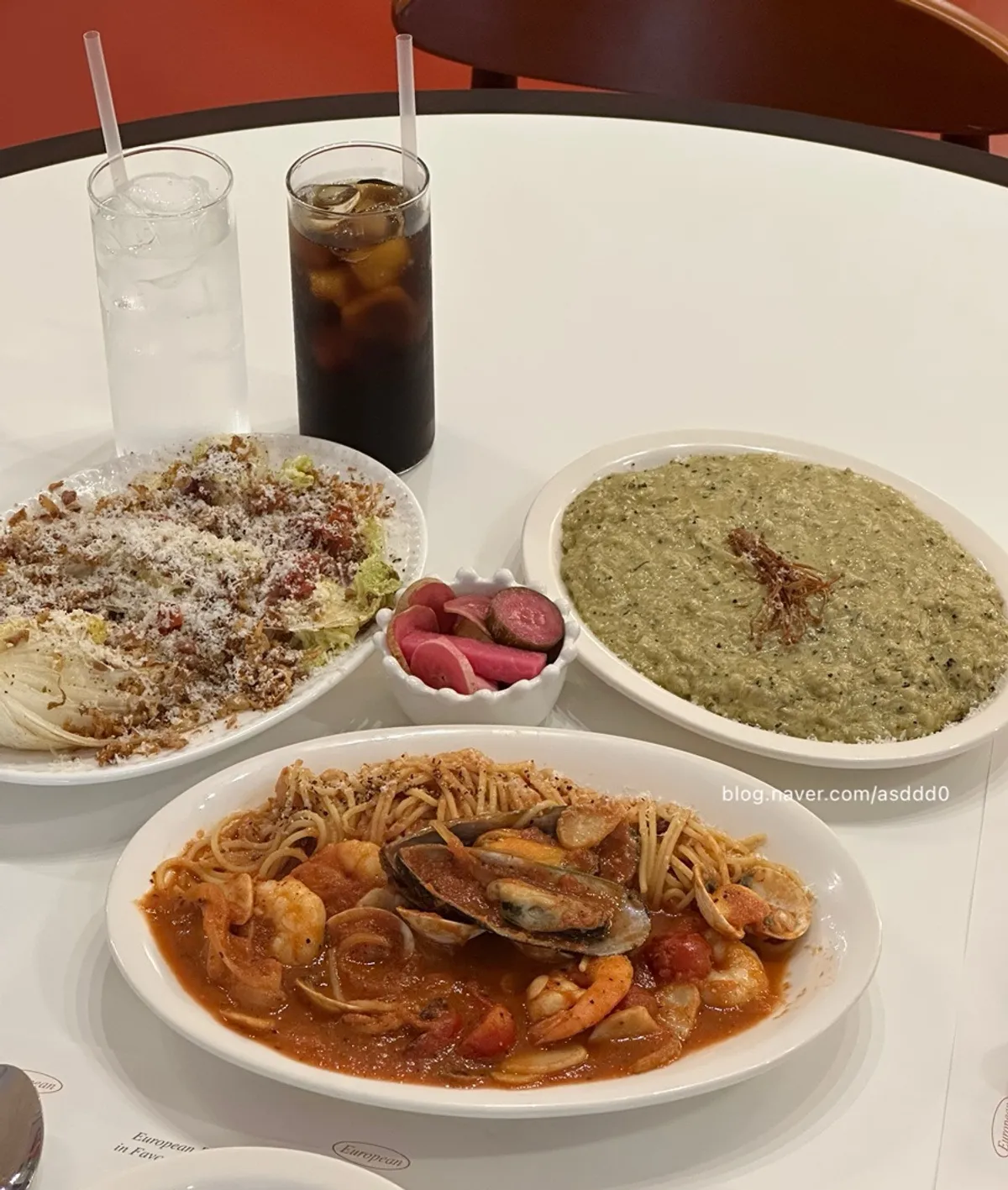 Table spread with napa cabbage Caesar salad, seafood tomato pasta, and abalone cream risotto